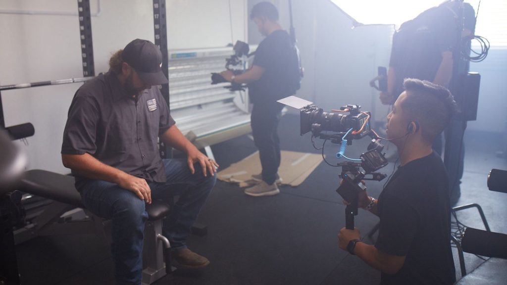 Behind-the-scenes of a video production session with crew and equipment in a modern studio setting.
