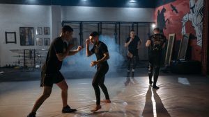 Intense MMA sparring session with fighters training in a dimly lit gym.